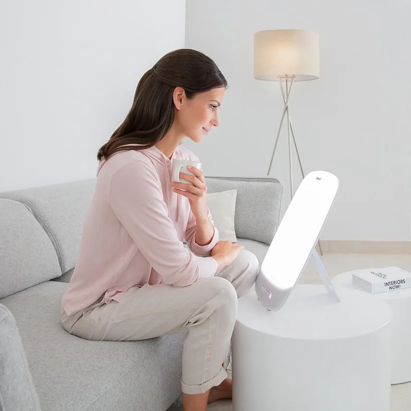 Femme utilisant la lampe de luminothérapie Beurer TL 85 dans son salon
